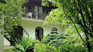 Ein Gebäude mit einer Treppe, die zu einem Balkon führt, umgeben von üppigem Grün.
