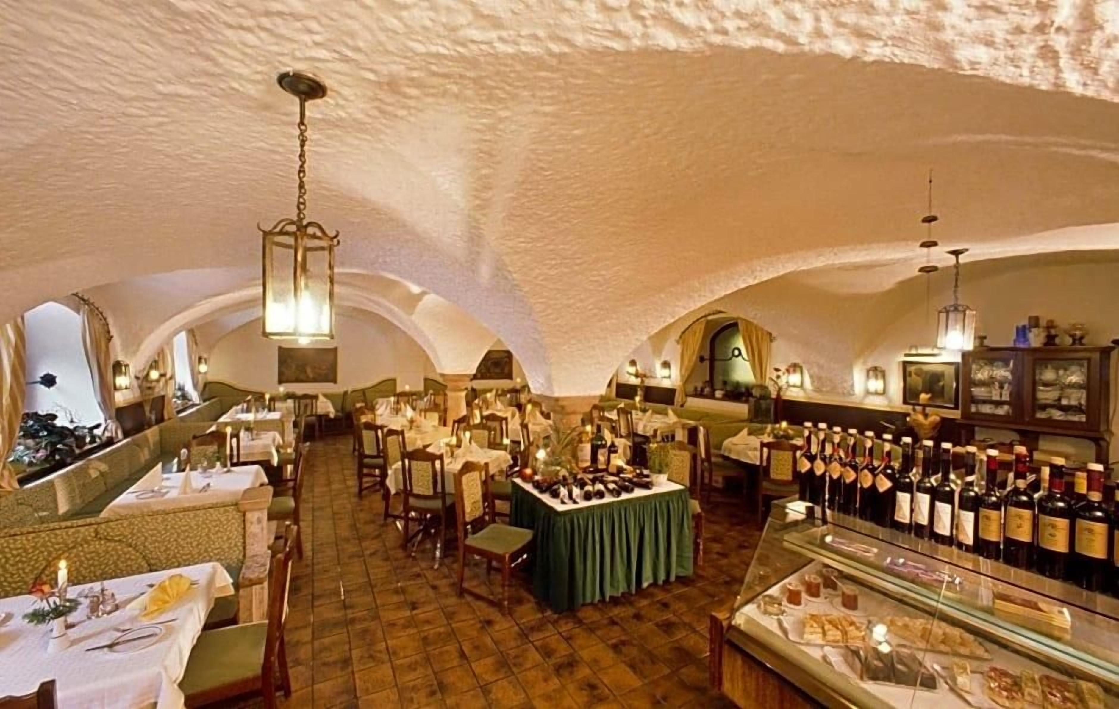 An indoor dining area with tables set for service, a bar area with bottles, and a display case with food items.