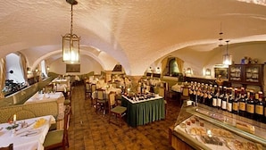 An indoor dining area with tables set for service, a bar area with bottles, and a display case with food items. - Grünes Türl (Bad Schallerbach)