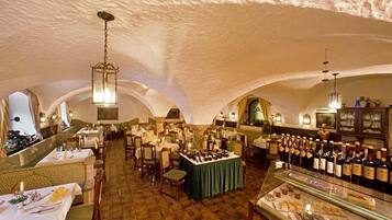 An indoor dining area with tables set for service, a bar area with bottles, and a display case with food items.