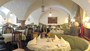 A restaurant with round tables, chairs, and a green cushioned bench. - Grünes Türl (Bad Schallerbach)