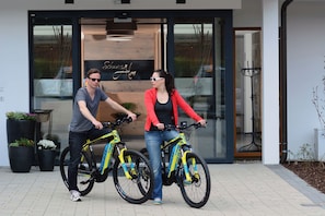 Dos personas en bicicleta frente a un edificio con un letrero que dice 'Schwarzmüller'.
