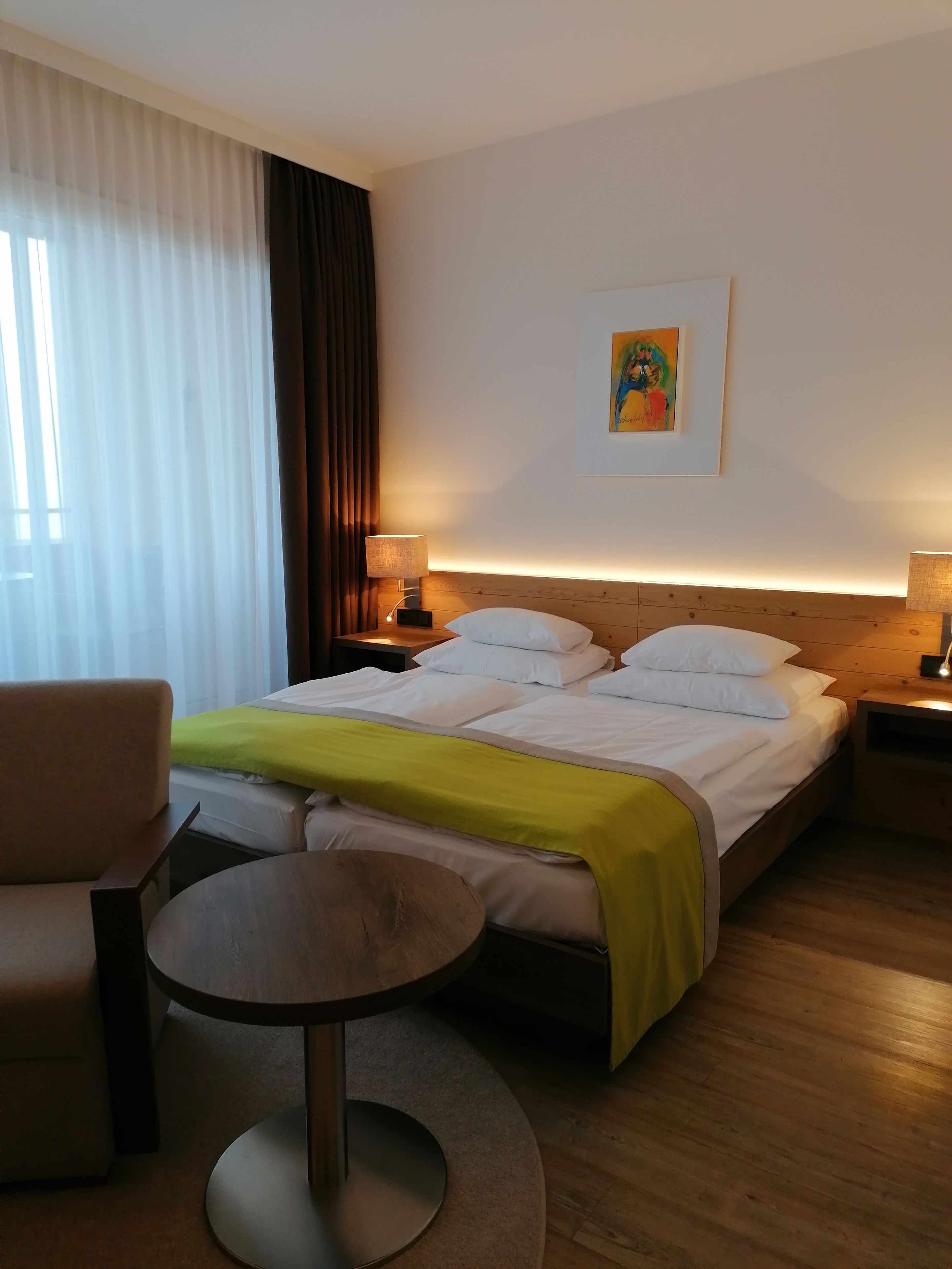 Ein Hotelzimmer mit einem Bett, einem Sessel, einem kleinen Tisch und einem Bild an der Wand.