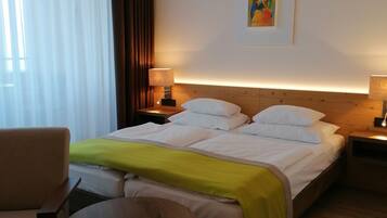 Ein Hotelzimmer mit einem Bett, einem Sessel, einem kleinen Tisch und einem Bild an der Wand.