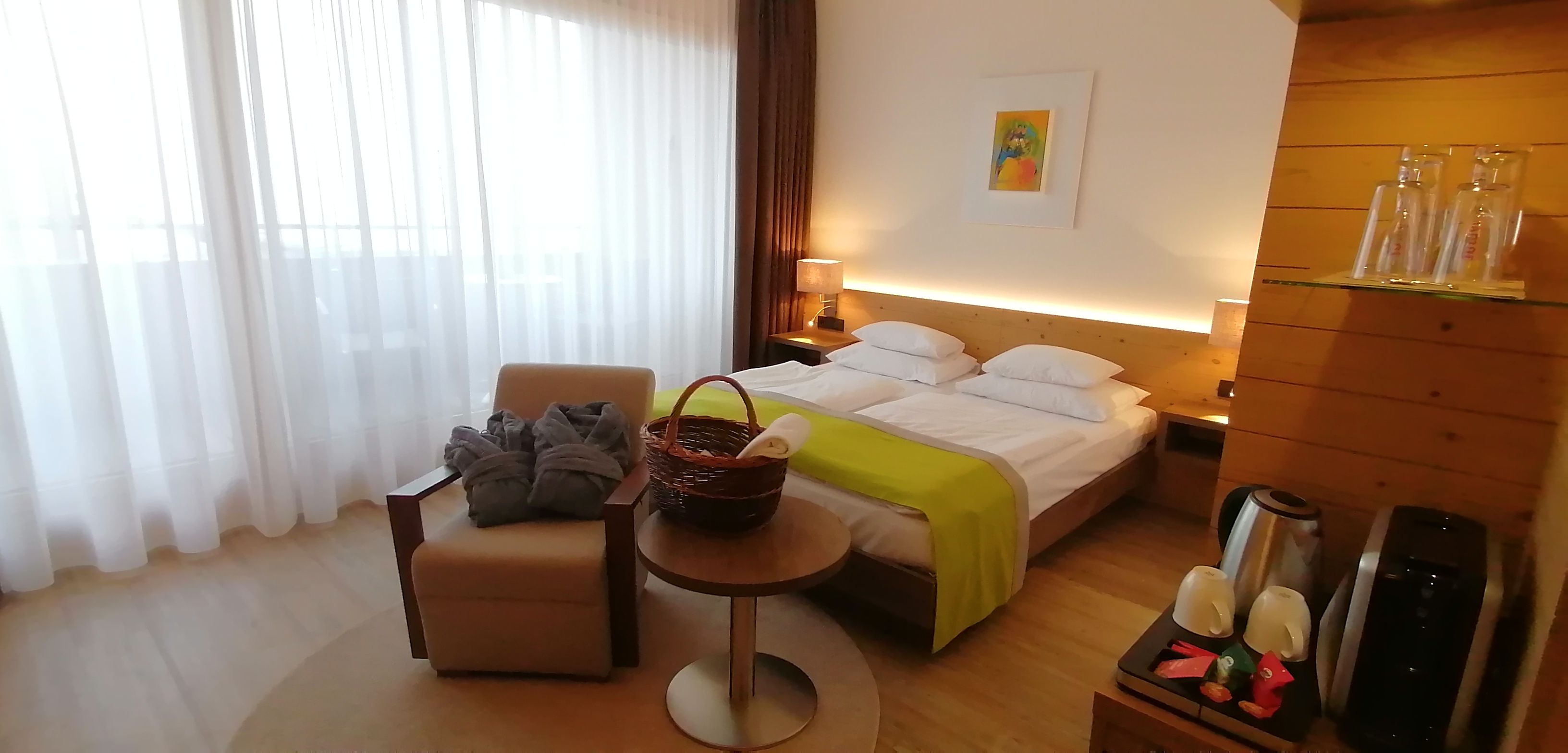 A hotel room with a bed, a chair, a small table, and a nightstand.