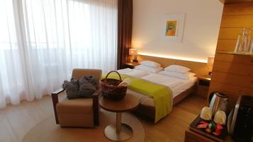 A hotel room with a bed, a chair, a small table, and a nightstand.