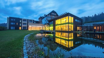 Ein modernes Gebäude mit einem spiegelnden Pool, umgeben von einem gepflegten Rasen und blauem Himmel.