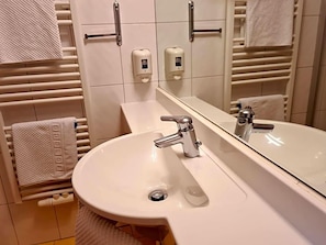 A bathroom with a white sink, a mirror, and towel racks.