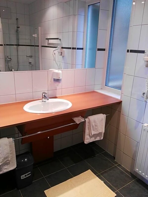 A bathroom with a sink, mirror, towel rack, and a window.