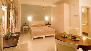 A bedroom with a bed, bedside table, and a small table with fruit and candles. - Nikolas Villas Kamilari (Faistos)