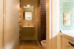 A narrow bathroom with a sink, mirror, and toilet. - Nikolas Villas Kamilari (Faistos)