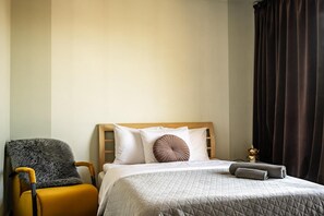 Una habitación de hotel con una cama, una silla y un ventanal con cortinas.
