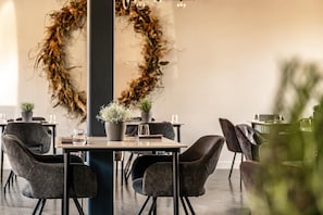A dining area with round tables, chairs, and a central column.