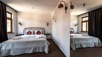 A double room with two beds, a radiator, a window with curtains, and wall-mounted lighting.