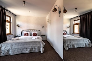 Habitación doble con dos camas, un radiador, una ventana con cortinas e iluminación en la pared.