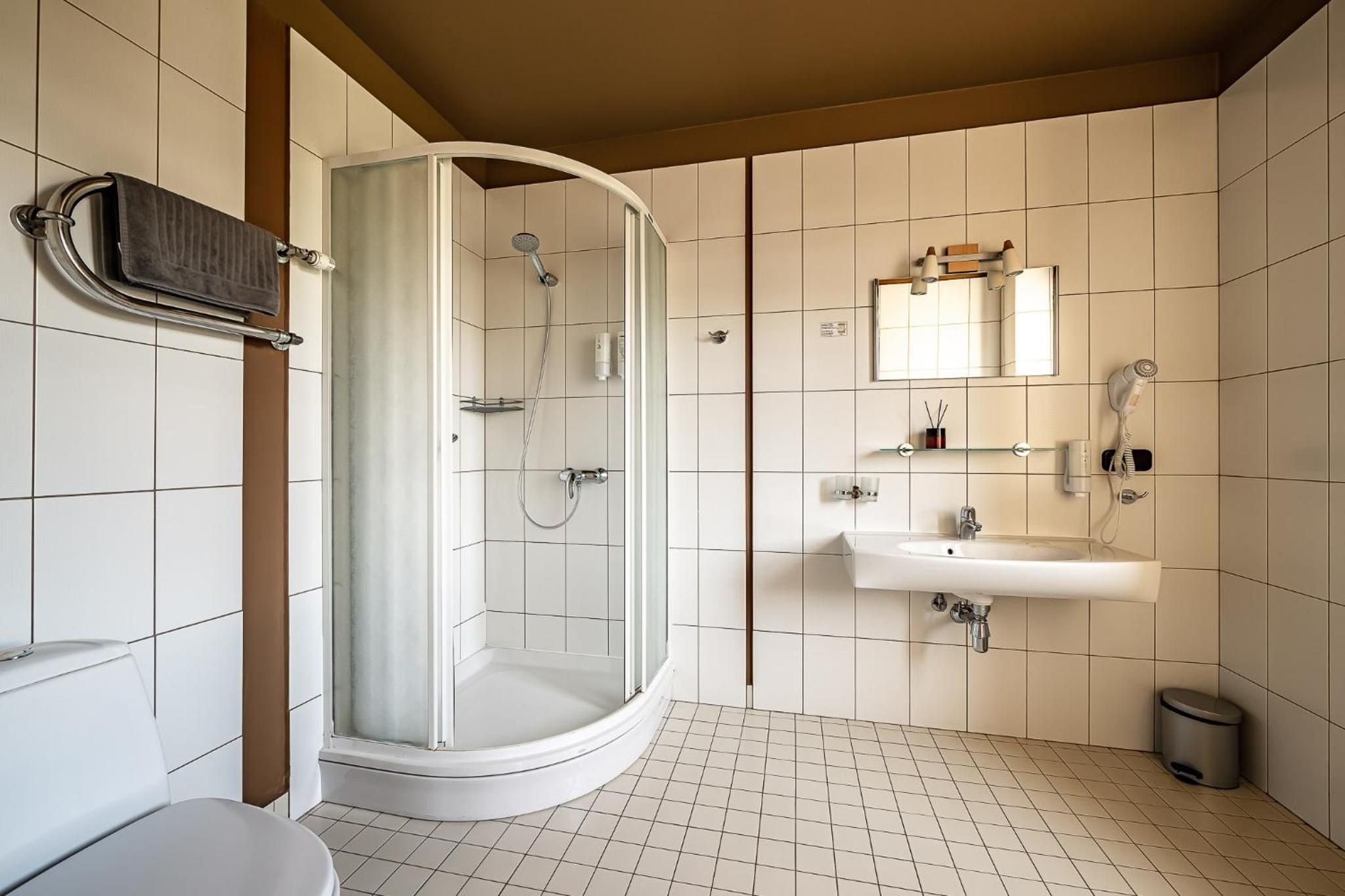 Ein modernes Badezimmer mit einer einachigen Duschkabine, einem weißen Waschbecken und einem Spiegel darüber.