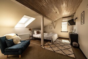 Un dormitorio con techo estilo loft, una cama, un sofá y una zona de escritorio.