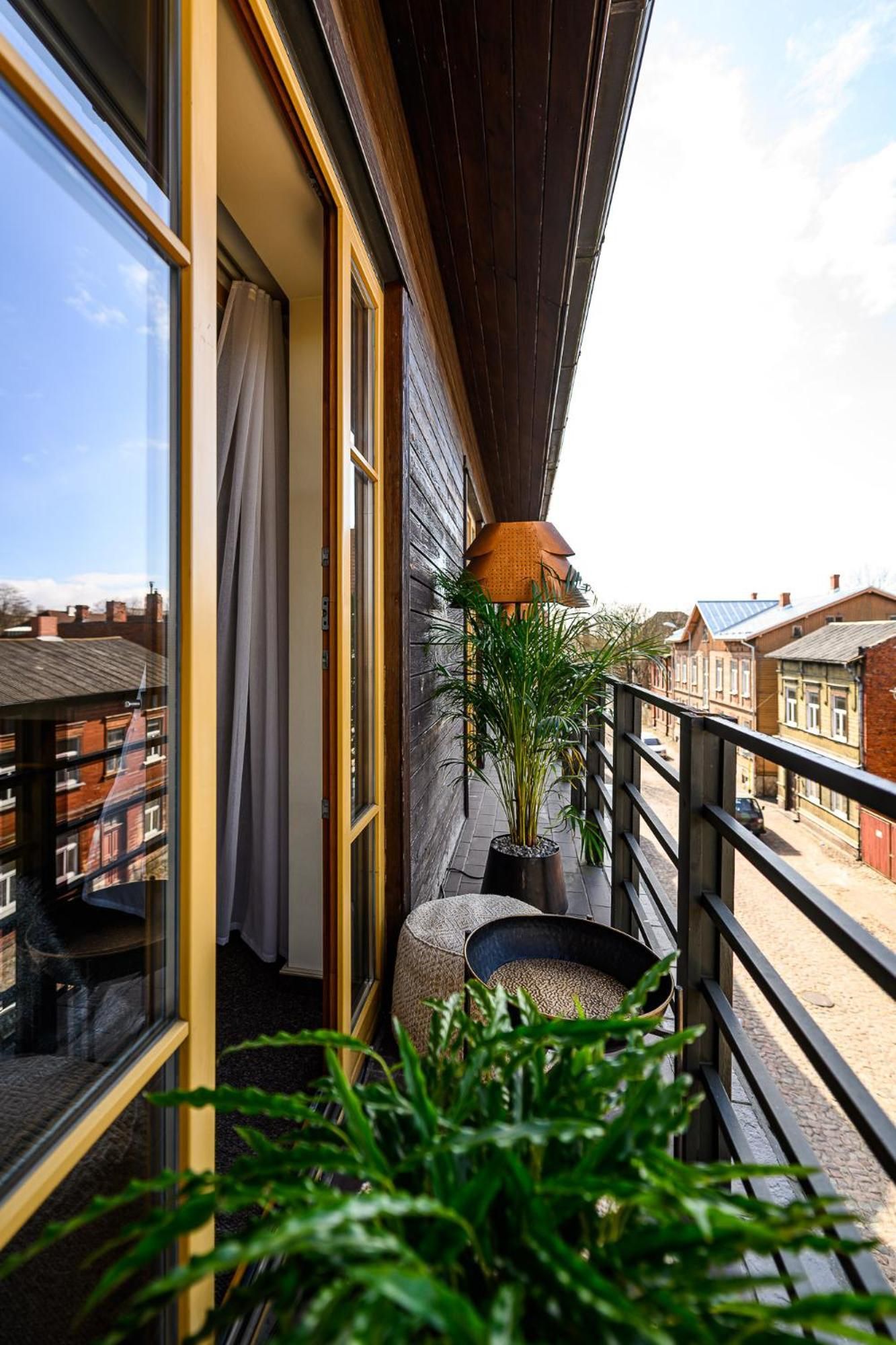 A balcony with a view of residential buildings, a potted plant, and a small seating area.