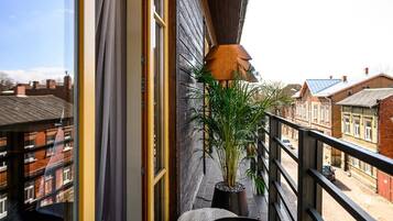 A balcony with a view of residential buildings, a potted plant, and a small seating area.