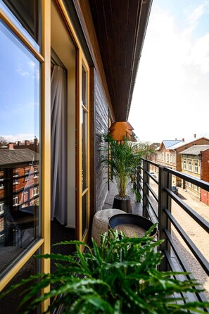Un balcón con vista a edificios residenciales, una planta en maceta y un pequeño espacio para sentarse.