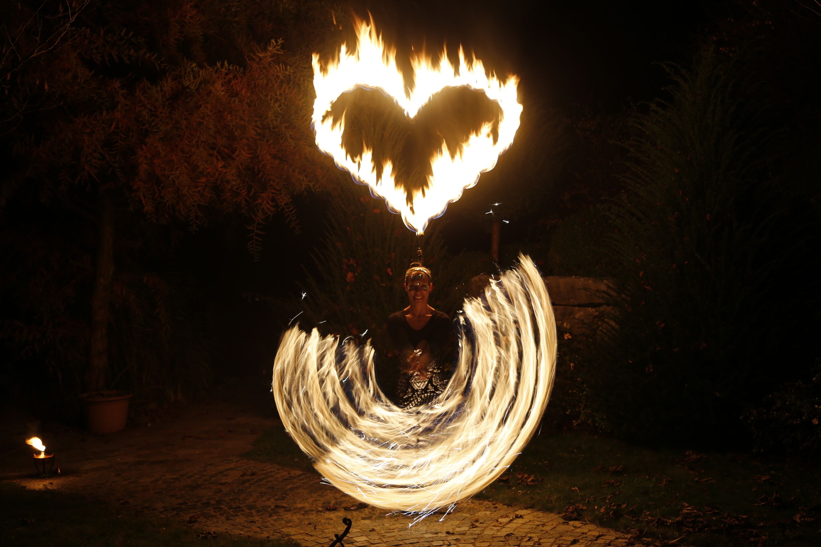 Una persona haciendo malabares con fuego, con una llama en forma de corazón sobre su cabeza.