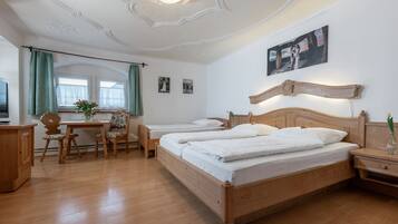 Een hotelkamer met twee houten bedden, een bureau met stoel, een televisie en een raam met gordijnen.