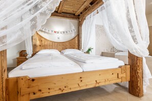 Ein hölzernes Bett mit weißen Leinen und durchsichtigen weißen Vorhängen, mit einem Schild, auf dem 'JUST MARRIED' steht.