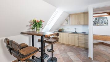 A modern kitchen with wooden cabinets, a dining area with a table and bar stools, and a skylight.