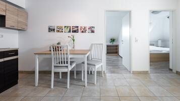 A modern kitchen with white cabinets and a dining area with a wooden table and white chairs.