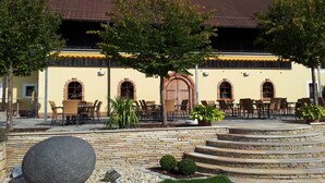 Un patio exterior con escalones de piedra, mobiliario para exteriores y un edificio con ventanas de arco y tejado de baldosas.