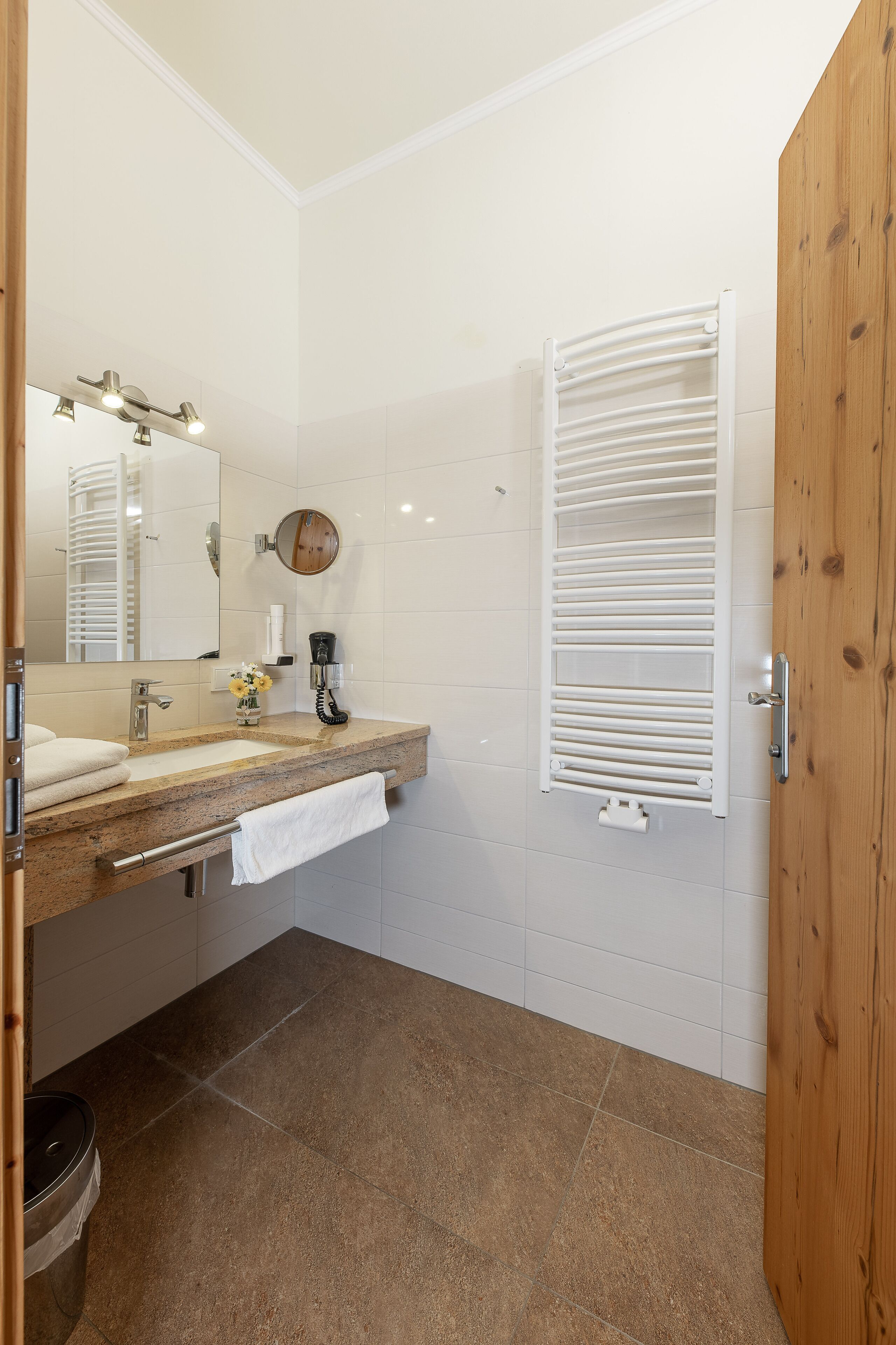 A bathroom with a sink, mirror, towel rack, and a white towel on the counter.