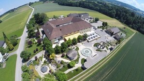 Vista aérea de una extensa propiedad con una edificación principal, jardines ajardinados y campos circundantes.