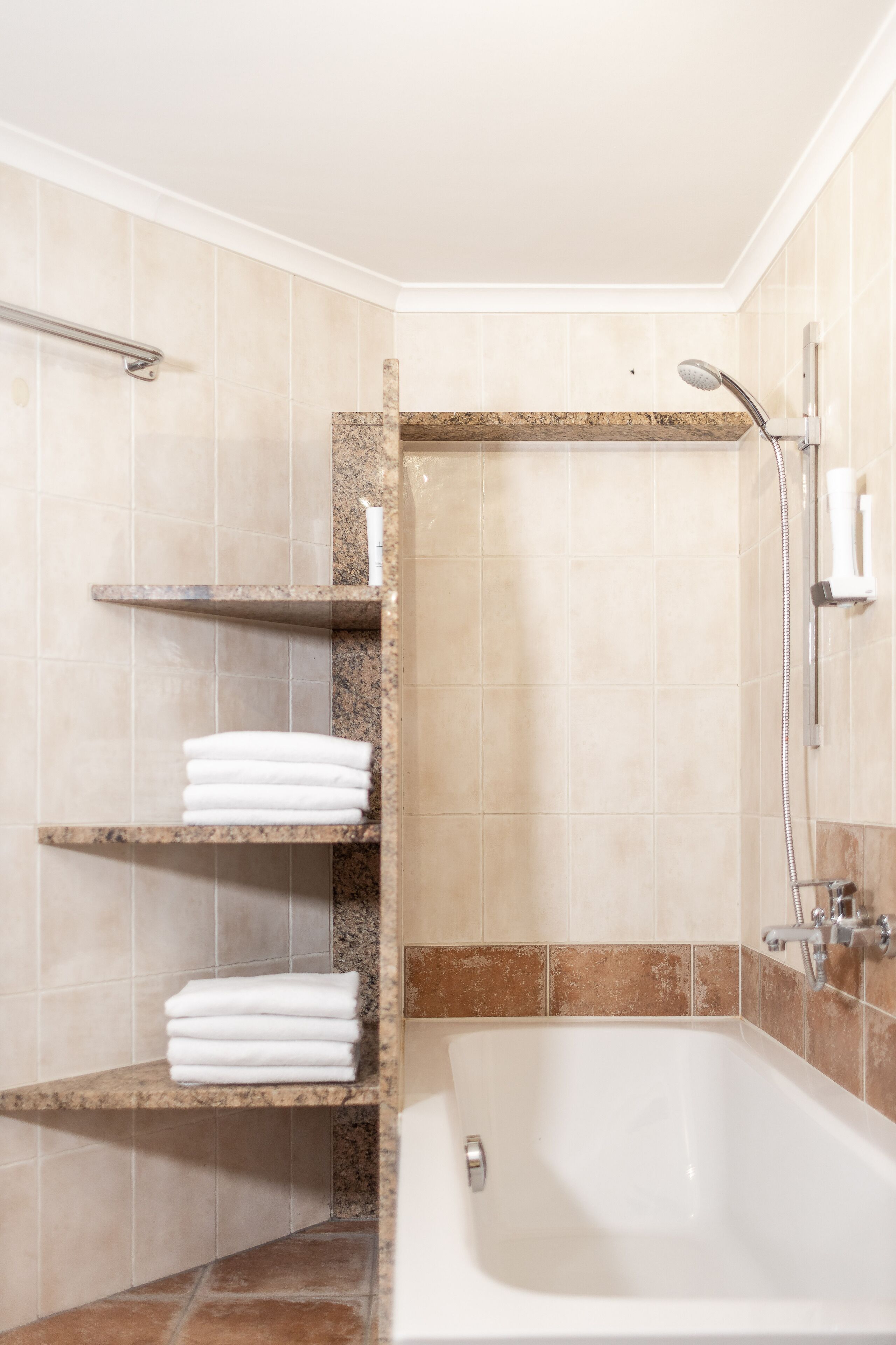 A bathroom with a bathtub, shelves with towels, and a shower area.