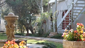 A courtyard with a fountain, a potted plant, and a staircase.