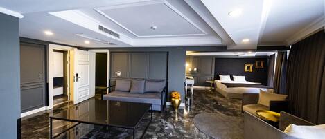 Una habitación de hotel moderna con una zona de estar amplia, un sofá, una mesa de centro y una mesa de comedor.