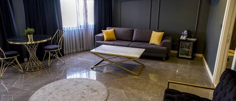 A modern living room with a sofa, a coffee table, a round rug, and a dining area with a small table and chairs.