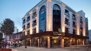 Un hotel de estilo arquitectónico clásico, con amplias ventanas en arco y un llamativo letrero que dice 'LOFT HOTEL'.