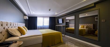 Una habitación de hotel moderna con una cama grande, una mesita, un espejo y un televisor.