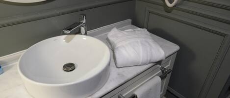 Une salle de bain avec un lavabo blanc, un porte-serviettes et un téléphone.