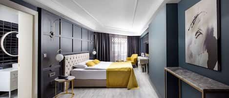 A modern hotel room with a bed, bedside table, and a desk with a chair.