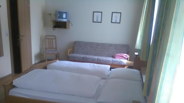 A room with two beds, a television on a shelf, and two framed pictures on the wall. - Gasthof Schatzl (Grieskirchen)