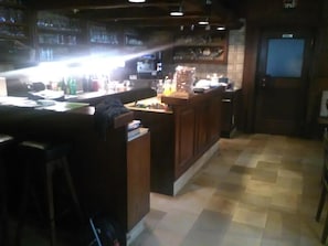 Zona de bar con mostrador, taburetes y piso de baldosas.