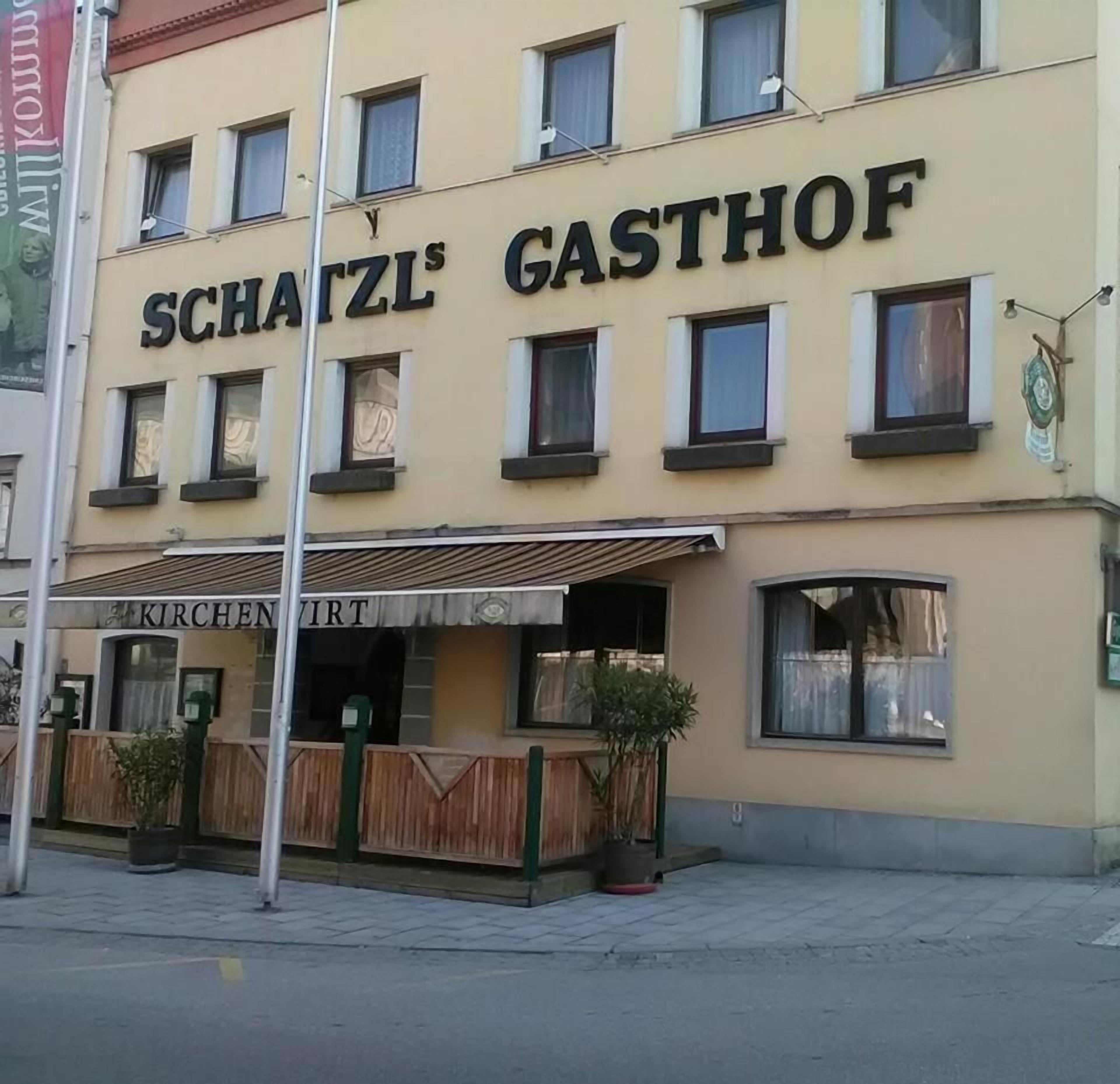 Un edificio con un letrero que dice 'SCHATZL'S GASTHOF' y un letrero más pequeño debajo que dice 'KIRCHENIRT'.