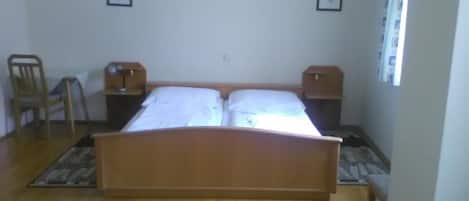 Un dormitorio con una cama de madera, dos mesitas de noche, una silla y una ventana con cortinas.