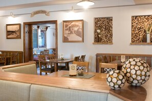A dining area with wooden furniture, a sign reading 'HAUSSTÜBERL', and framed pictures on the wall.