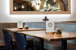 A restaurant interior with wooden tables, chairs, and a modern chandelier.