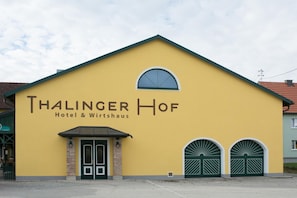 A yellow building with the sign 'Thalinger Hof Hotel & Wirtshaus' and two green double doors.