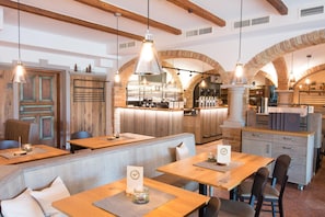 A restaurant interior with wooden tables, benches, and arched brick walls.