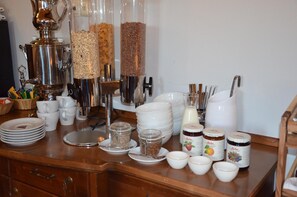 A breakfast buffet setup with various food items, utensils, and containers.