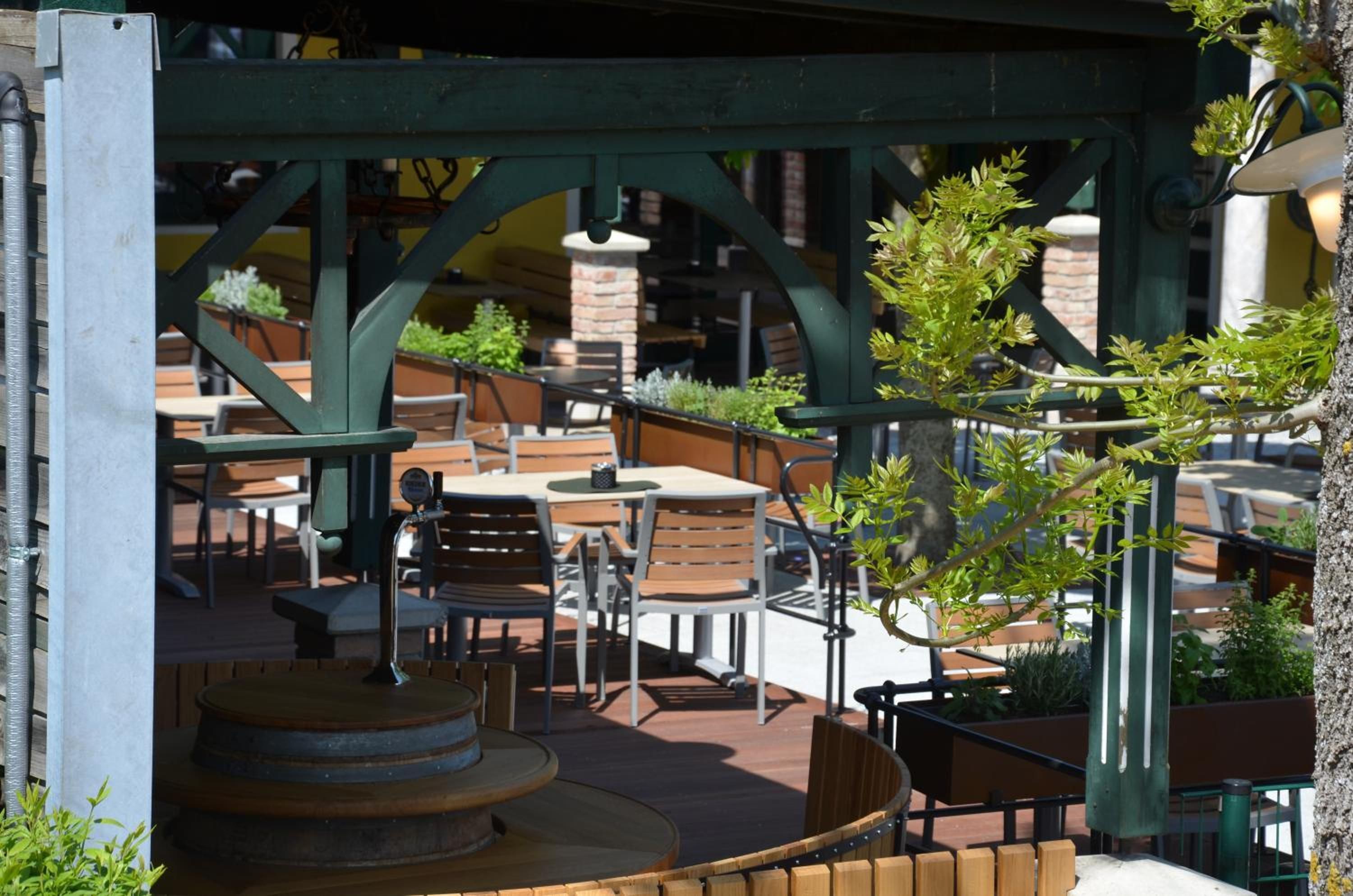 An outdoor patio area with tables and chairs, a small fountain, and potted plants.